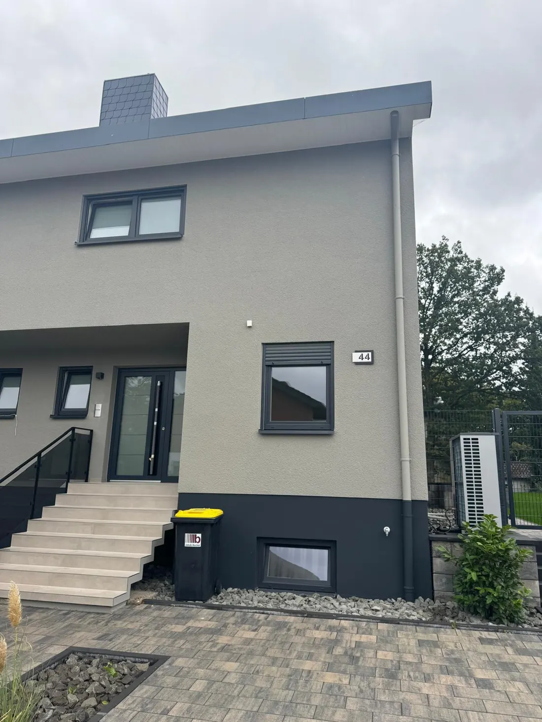 Eingangsseite des Hauses mit Treppe und Außengerät der Wärmepumpe